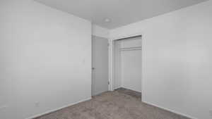 Unfurnished bedroom with light colored carpet and a closet