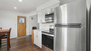 Kitchen featuring white cabinets, stainless steel appliances, and dark wood-type flooring