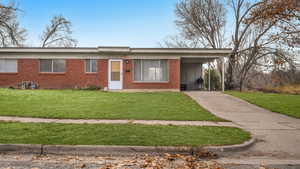 Ranch-style house featuring a carport and a front lawn