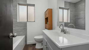 Bathroom featuring a tub to relax in, vanity, hardwood / wood-style flooring, and toilet