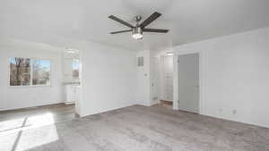 Interior space featuring ensuite bathroom, ceiling fan, and light carpet