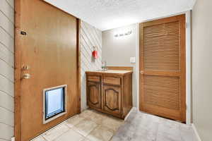 Bathroom featuring vanity, a textured ceiling, and wooden walls