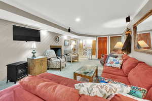 Carpeted living room featuring a wood stove and wooden walls