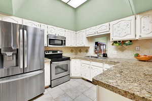 Kitchen featuring white cabinetry, decorative backsplash, sink, and stainless steel appliances