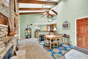 Dining room with beam ceiling, light carpet, high vaulted ceiling, and ceiling fan