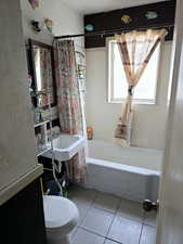 Bathroom featuring tile patterned floors, shower / bath combo, and toilet