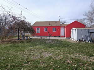 Back of property featuring a storage unit and a lawn