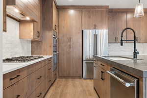 Kitchen featuring dark stone counters, a sink, stainless steel appliances, and decorative backsplash