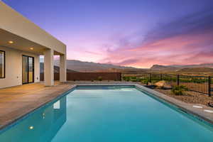 Pool at dusk with a mountain view, a fenced backyard, a fenced in pool, and a patio area