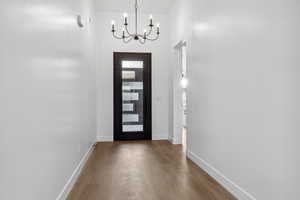 Entrance foyer featuring a chandelier, wood finished floors, and baseboards
