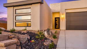 View of front of house featuring concrete driveway, stone siding, an attached garage, and stucco siding
