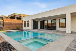 View of pool with fence, a pool with connected hot tub, and a patio area