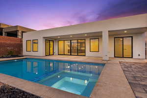 Back of house featuring stucco siding, fence, a fenced in pool, a patio, and an in ground hot tub