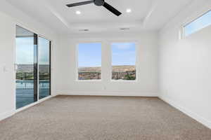 Carpeted spare room featuring ceiling fan, a raised ceiling, and visible vents