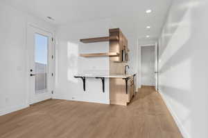 Kitchen featuring open shelves, light countertops, baseboards, recessed lighting, and light wood finished floors