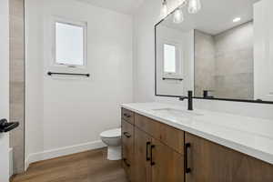 Bathroom with baseboards, wood finished floors, toilet, and vanity