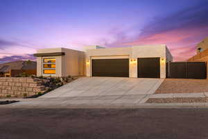 Modern home featuring driveway, fence, stucco siding, and an attached garage