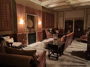 Carpeted home theater room with a tile fireplace, beam ceiling, and coffered ceiling
