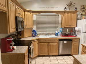 Kitchen featuring light tile patterned flooring, sink, and stainless steel appliances