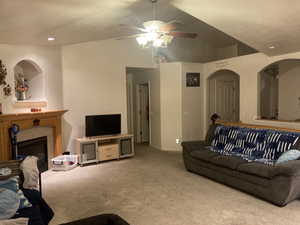 Carpeted living room featuring ceiling fan, a textured ceiling, and a tile fireplace