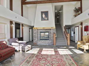 Living room featuring a stone fireplace, beamed ceiling, and high vaulted ceiling