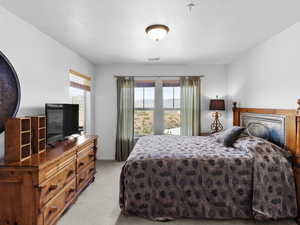 Carpeted bedroom featuring a textured ceiling and multiple windows