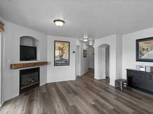 Unfurnished living room with wood-type flooring and a textured ceiling