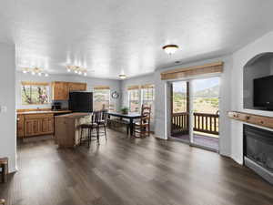 Kitchen with a breakfast bar, dark wood-type flooring, black refrigerator, sink, and a textured ceiling