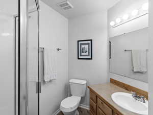 Bathroom featuring hardwood / wood-style floors, vanity, an enclosed shower, and toilet