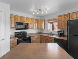 Kitchen with black appliances, sink, and a textured ceiling