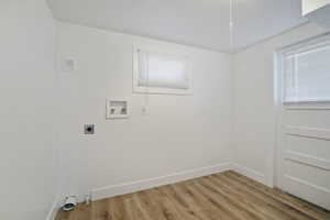 Washroom with electric dryer hookup, hookup for a washing machine, light hardwood / wood-style floors, and a textured ceiling