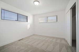 Unfurnished bedroom with light carpet and a closet