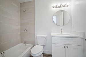 Full bathroom featuring hardwood / wood-style floors, vanity, toilet, and tiled shower / bath