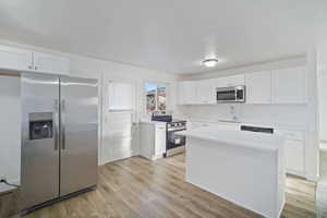 Kitchen featuring white cabinetry, sink, stainless steel appliances, light hardwood / wood-style flooring, and a kitchen island