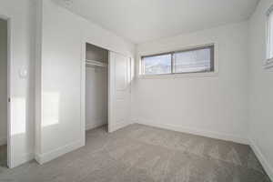 Unfurnished bedroom with light colored carpet and a closet