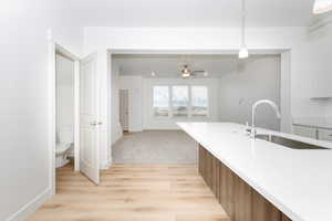 Kitchen featuring ceiling fan, light hardwood / wood-style floors, sink, and hanging light fixtures