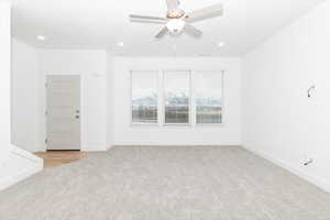 Empty room featuring light colored carpet and ceiling fan