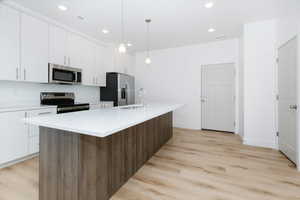 Kitchen with appliances with stainless steel finishes, a center island with sink, white cabinetry, and sink