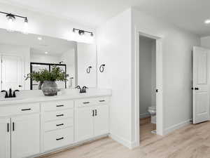 Bathroom with toilet, vanity, and hardwood / wood-style flooring