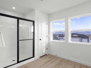 Interior space with a shower with shower door and wood-type flooring