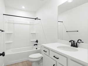 Full bathroom with hardwood / wood-style floors, vanity, toilet, and tub / shower combination