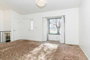 Foyer entrance with carpet floors and an inviting chandelier