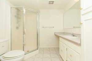 Bathroom with tile patterned floors, vanity, toilet, and a shower with shower door