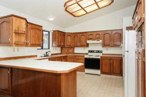 Kitchen featuring sink, white appliances, kitchen peninsula, and vaulted ceiling