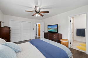 Primary Bedroom featuring a closet, ensuite bath, ceiling fan, and dark wood-style flooring