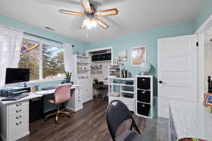 Spare bedroom used as office space featuring ceiling fan and dark wood-style floors