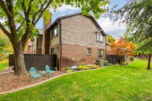 View of side of property with a lawn, flower beds, and central AC unit