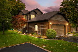 View of front facade featuring a garage and a yard