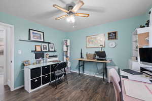 Spare bedroom used as office space featuring ceiling fan and dark wood-style floors