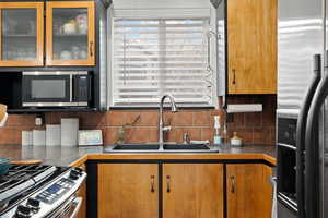 Kitchen featuring appliances with stainless steel finishes, backsplash, and sink